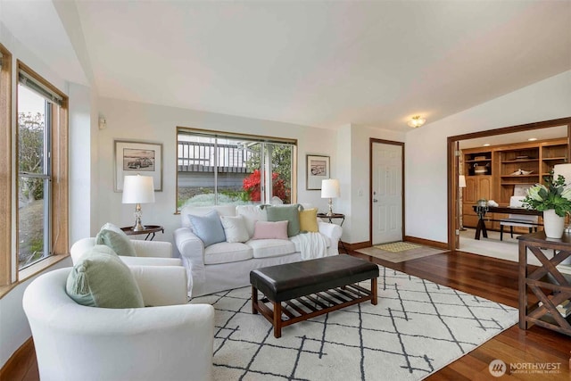 living area featuring light wood-style floors, plenty of natural light, lofted ceiling, and baseboards