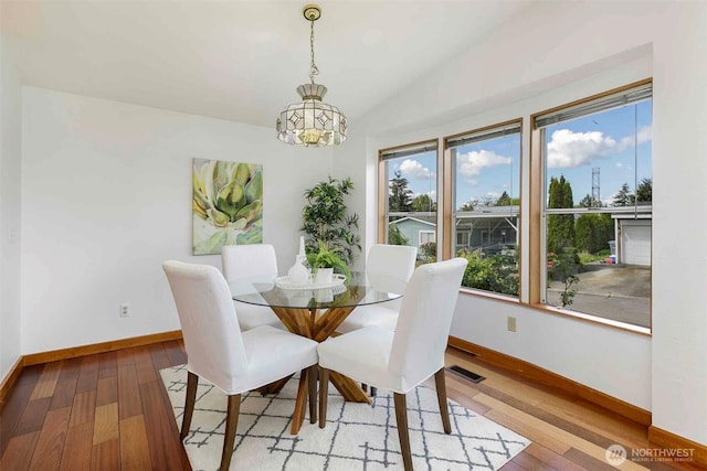 dining area with a chandelier, baseboards, hardwood / wood-style floors, and lofted ceiling