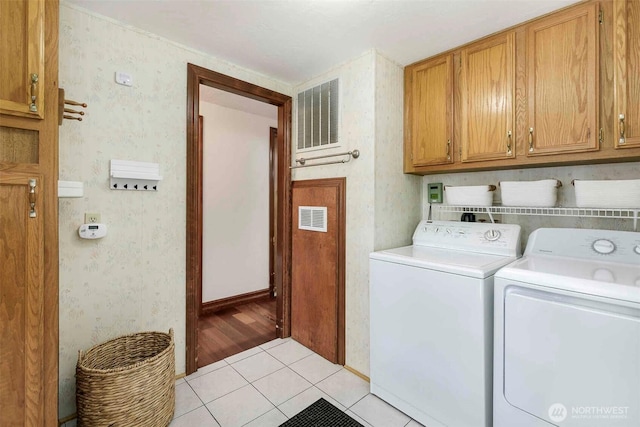 laundry room featuring cabinet space, separate washer and dryer, light tile patterned floors, and wallpapered walls