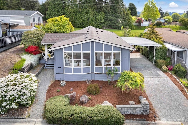 view of front facade with driveway, a carport, and roof with shingles