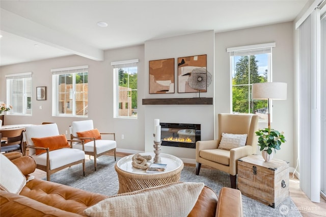 living room with light wood finished floors, a wealth of natural light, baseboards, and a glass covered fireplace