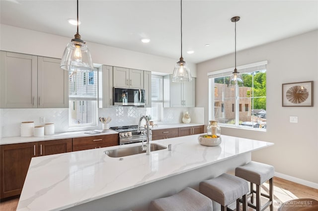 kitchen with baseboards, a breakfast bar, a sink, stainless steel microwave, and backsplash