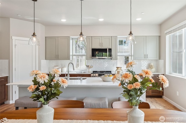 kitchen featuring stove, light countertops, a sink, and stainless steel microwave