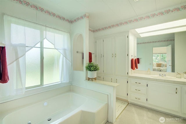 bathroom with connected bathroom, vanity, a healthy amount of sunlight, and a bath