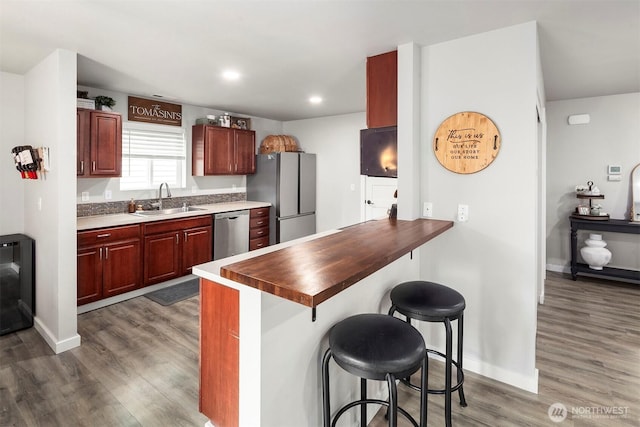 29058 215th Pl SE, Kent, WA 98042 - kitchen featuring appliances with stainless steel finishes, a sink, a kitchen bar, dark wood-style floors, and a peninsula