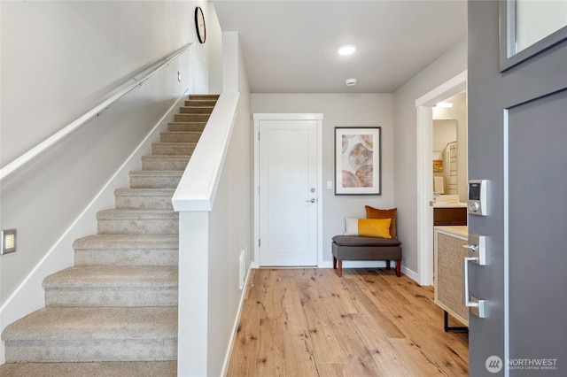 foyer with baseboards, stairway, and light wood-type flooring