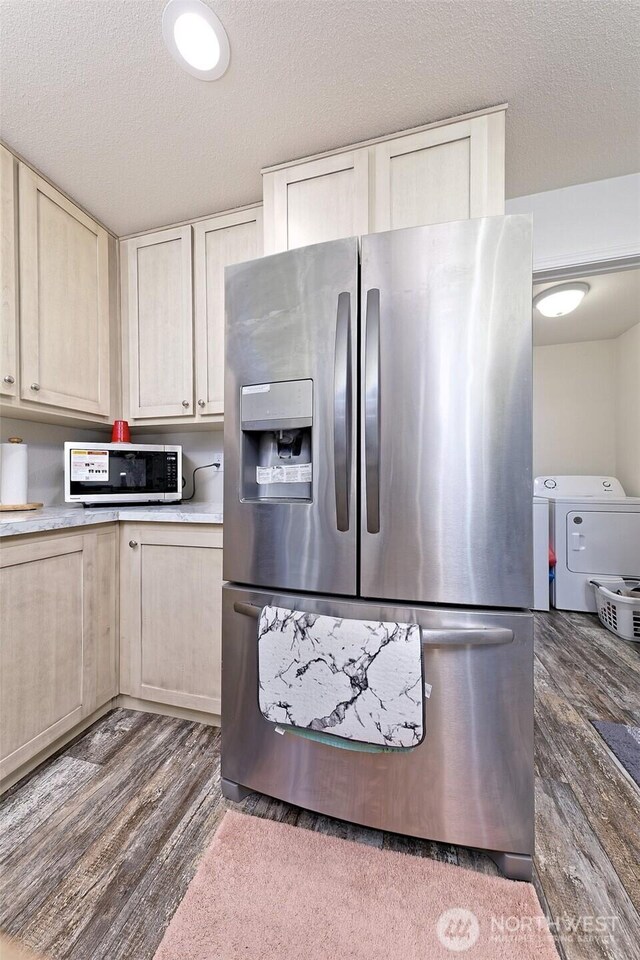 kitchen with stainless steel appliances, washer and dryer, dark wood finished floors, light countertops, and light brown cabinetry