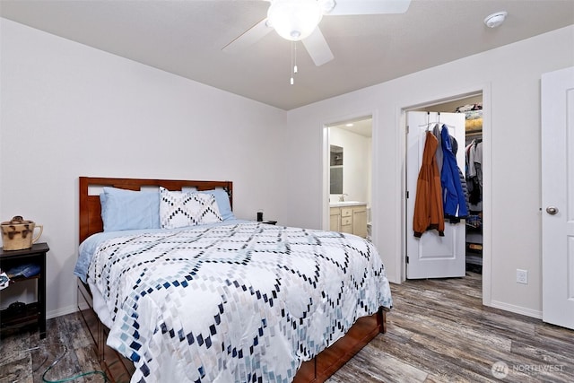 bedroom featuring a spacious closet, wood finished floors, and baseboards