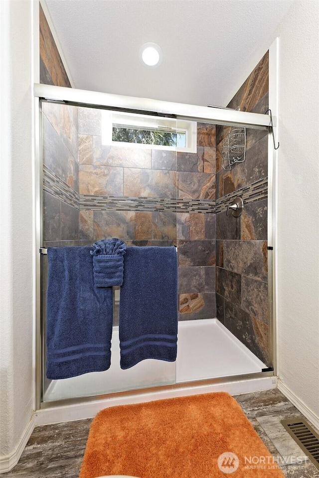 bathroom with a shower stall, wood finished floors, and baseboards