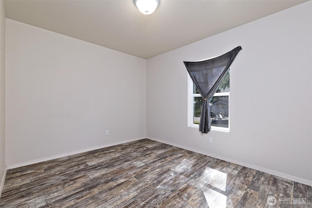 spare room featuring dark wood-style floors and baseboards