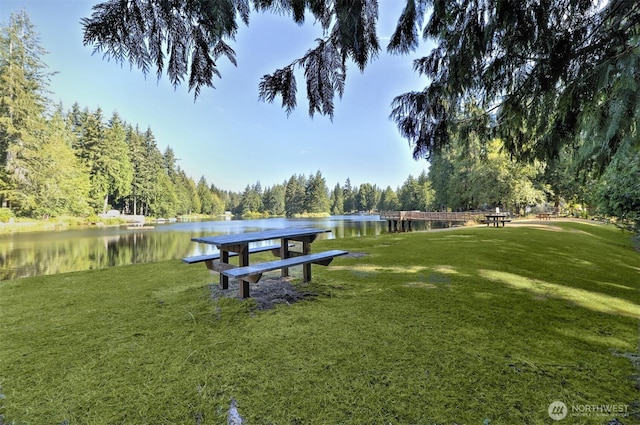 view of community with a lawn, a water view, and a view of trees