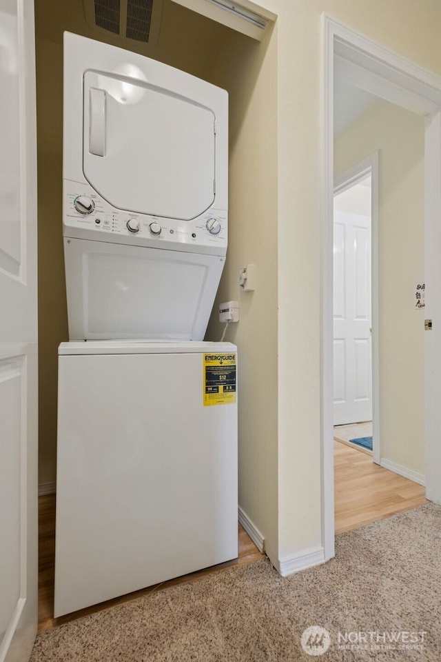 washroom featuring estacked washer and dryer, carpet, baseboards, and wood finished floors