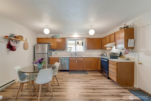 kitchen featuring appliances with stainless steel finishes, under cabinet range hood, a sink, a baseboard radiator, and light wood finished floors