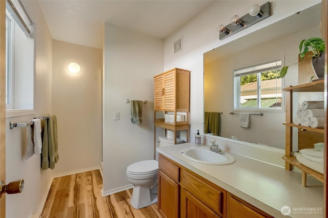 bathroom with wood finished floors, toilet, vanity, and baseboards