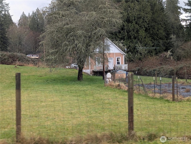 view of green lawn featuring a wooden deck and a view of trees