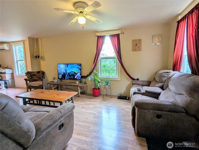 living area with wood finished floors, a wall mounted air conditioner, and ceiling fan