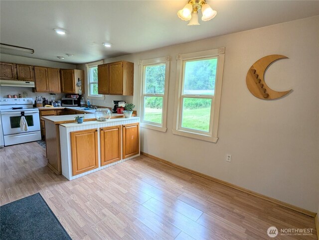kitchen with white range with electric stovetop, under cabinet range hood, a peninsula, and light wood-type flooring