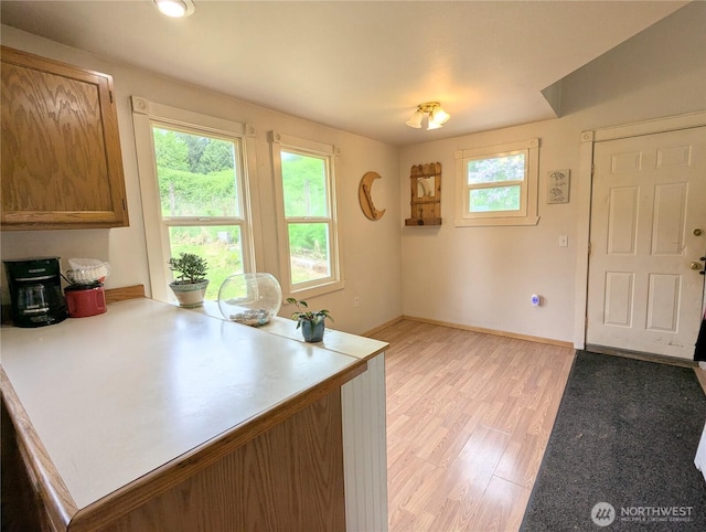 kitchen with light countertops, baseboards, light wood-type flooring, and a peninsula
