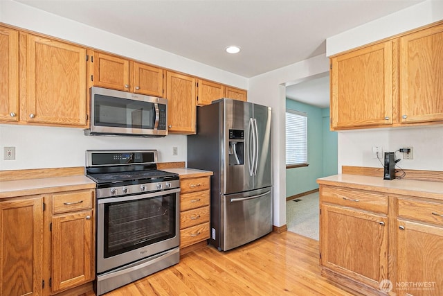 kitchen featuring stainless steel appliances, light countertops, light wood finished floors, recessed lighting, and baseboards