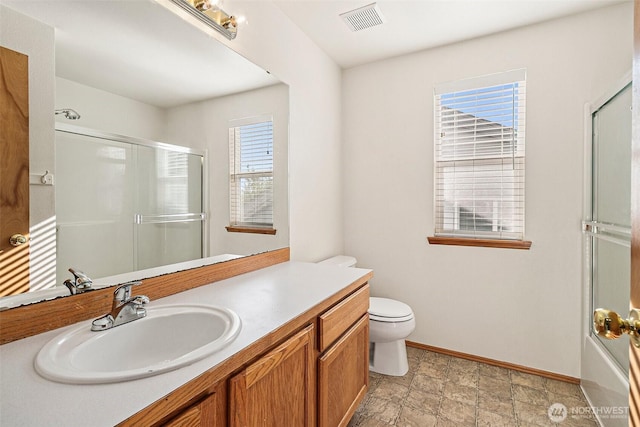 full bathroom featuring an enclosed shower, baseboards, toilet, vanity, and stone finish flooring