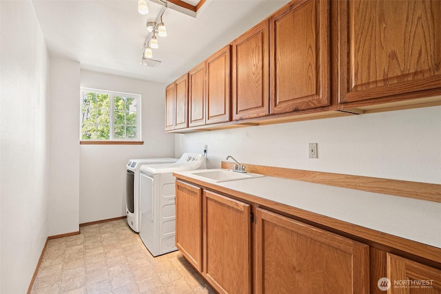 washroom featuring cabinet space, separate washer and dryer, baseboards, and rail lighting