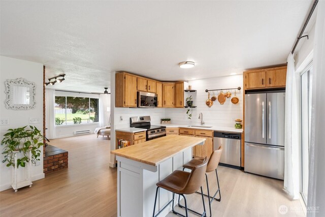kitchen with stainless steel appliances, open shelves, a sink, and light wood finished floors