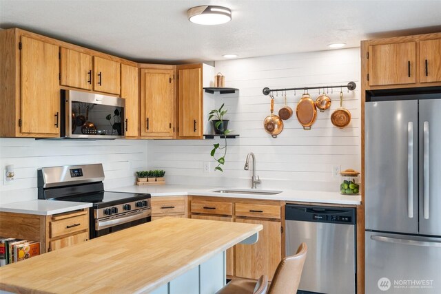 kitchen with stainless steel appliances, a sink, open shelves, a kitchen island, and butcher block counters