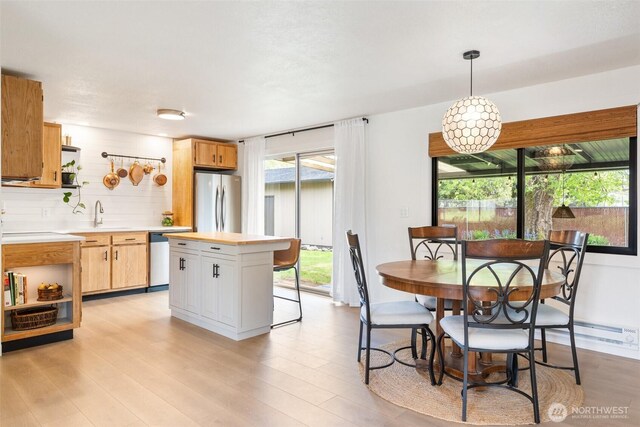 kitchen featuring open shelves, stainless steel appliances, light wood finished floors, hanging light fixtures, and a kitchen breakfast bar