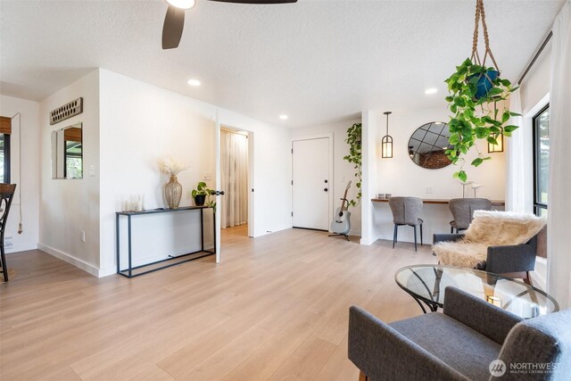 sitting room with light wood finished floors, a ceiling fan, plenty of natural light, recessed lighting, and baseboards