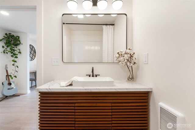 full bath featuring wood finished floors, vanity, and baseboards