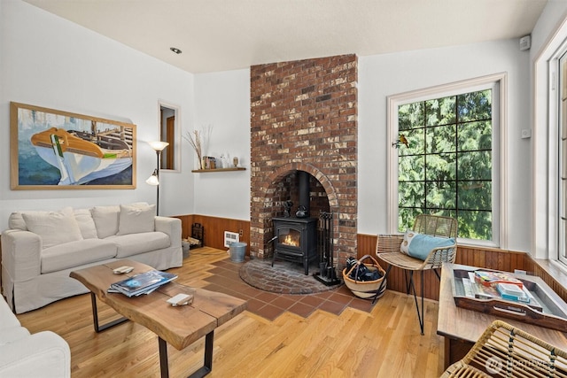 living area featuring a wood stove, wainscoting, wood finished floors, and wood walls