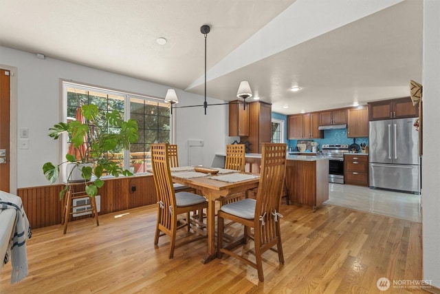 dining area with light wood finished floors and vaulted ceiling