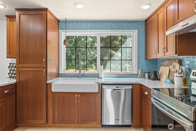 kitchen with stainless steel appliances, a sink, ventilation hood, brown cabinets, and light stone countertops