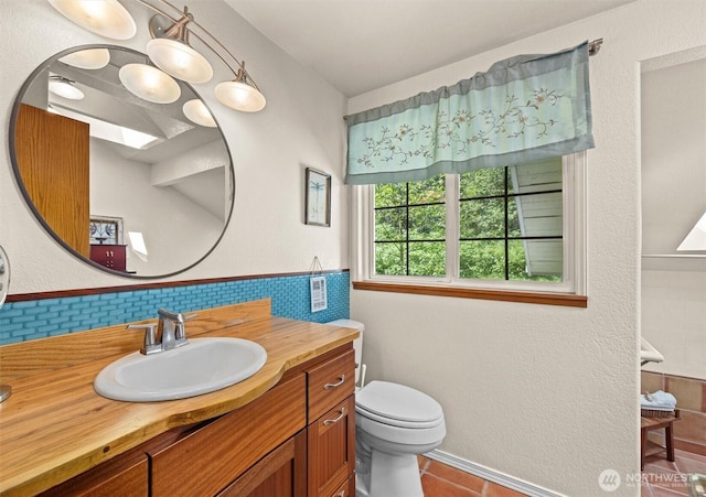 bathroom with toilet, vanity, tile patterned floors, and tile walls