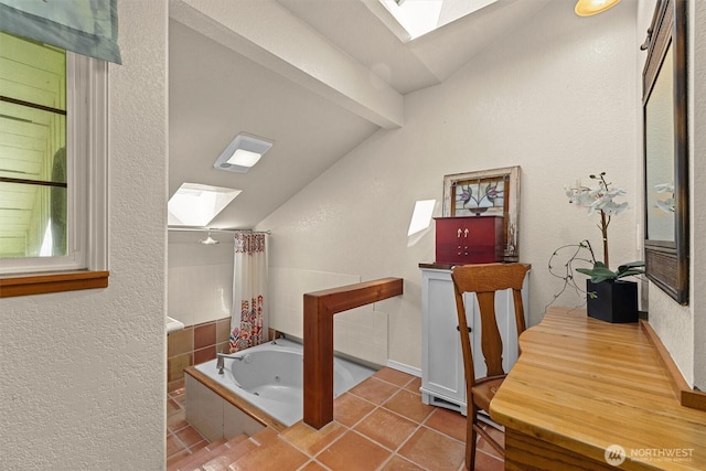 full bath featuring a skylight, lofted ceiling, a jetted tub, tile patterned flooring, and a textured wall