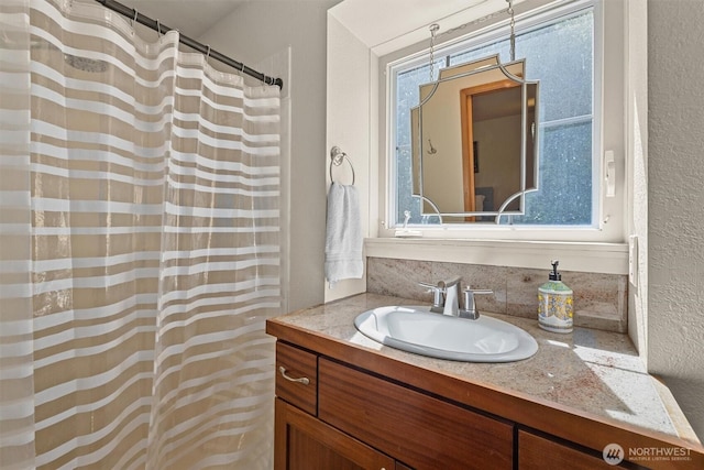 full bathroom featuring vanity, a textured wall, and curtained shower