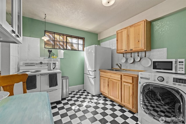 kitchen featuring washer / dryer, white appliances, light flooring, a sink, and light countertops