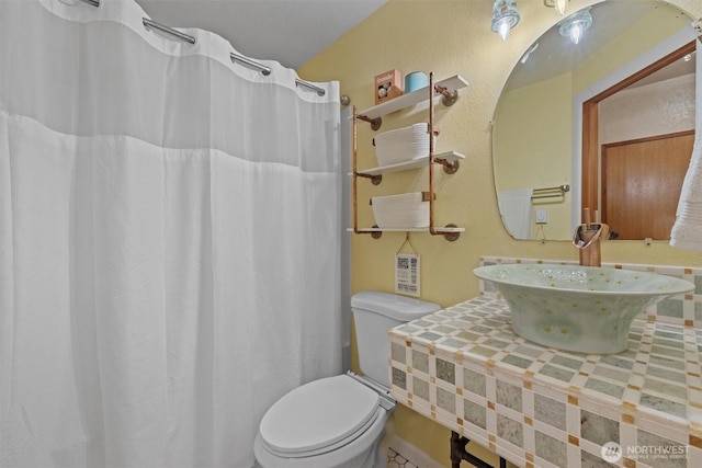 bathroom featuring toilet, a sink, and a shower with shower curtain