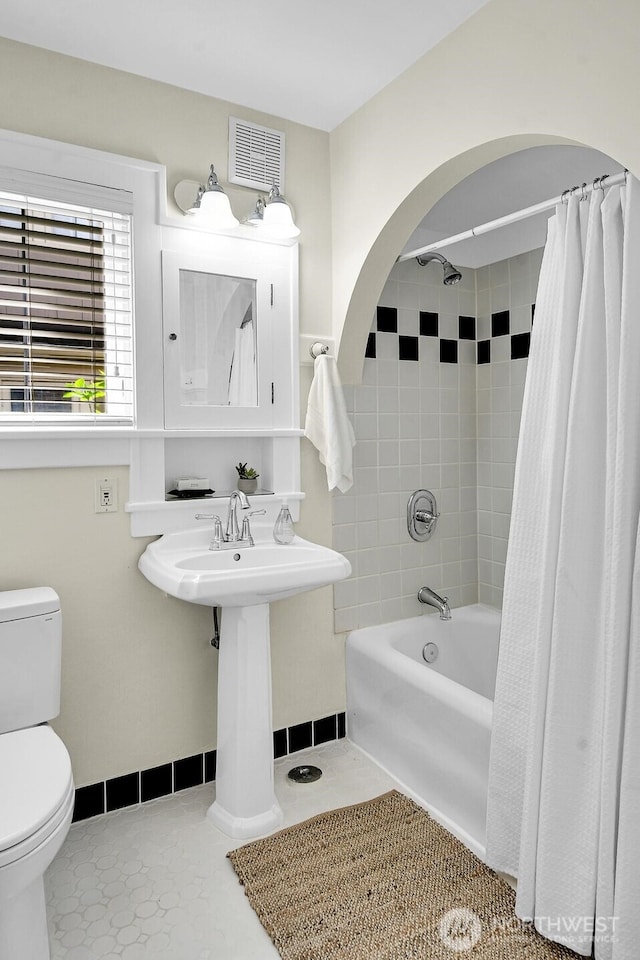full bathroom featuring toilet, shower / bath combo with shower curtain, and baseboards