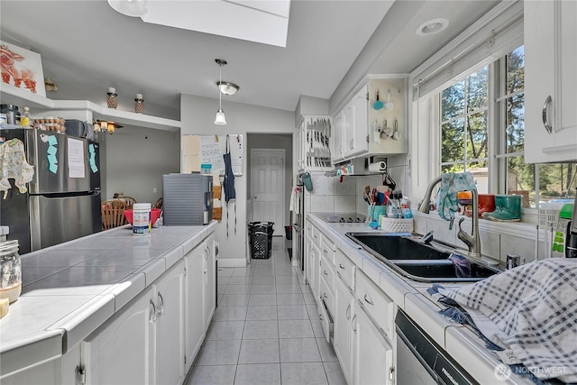 kitchen with light tile patterned floors, freestanding refrigerator, tile counters, white cabinets, and tasteful backsplash