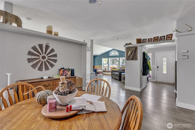 dining area featuring baseboards, vaulted ceiling, and wood finished floors