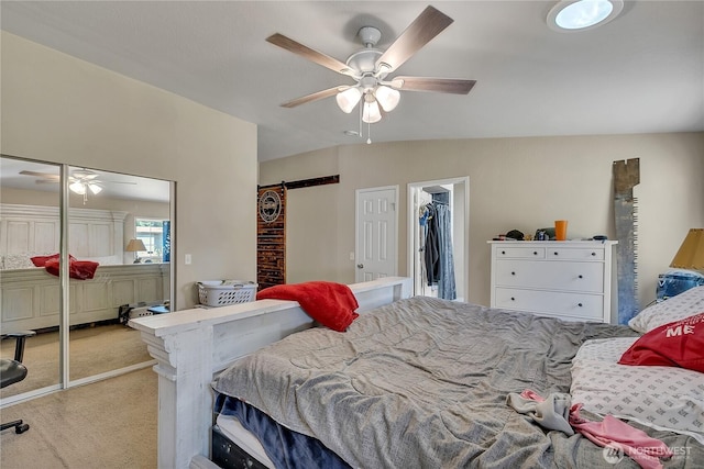 carpeted bedroom featuring lofted ceiling, a barn door, a closet, and a ceiling fan