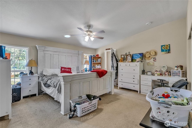 bedroom with a textured ceiling, light carpet, and a ceiling fan