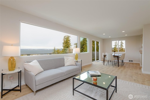 living area featuring light wood-style floors, visible vents, baseboards, and recessed lighting