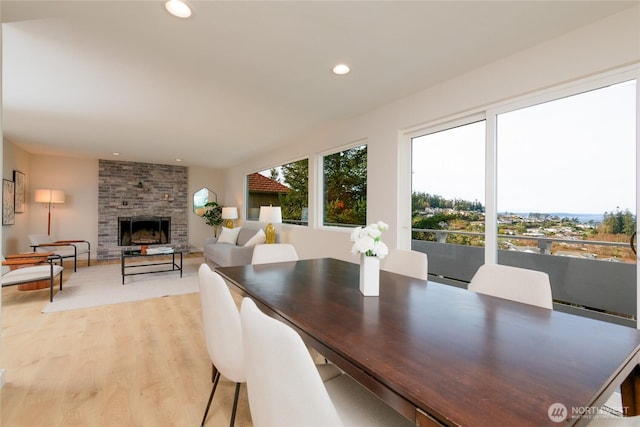 dining area featuring a fireplace, light wood-style flooring, and recessed lighting