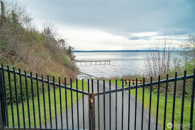 view of gate featuring a yard, a water view, and fence
