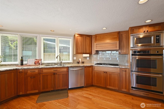 3911 NE 158th Ln, Lake Forest Park, WA 98155 - kitchen with stainless steel appliances, a sink, light wood-type flooring, a textured ceiling, and brown cabinetry