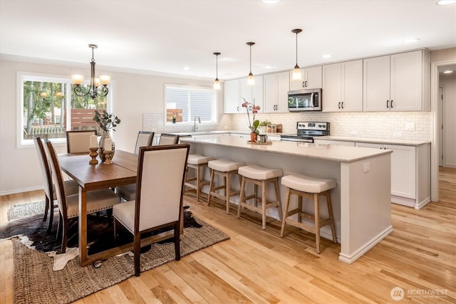 kitchen with appliances with stainless steel finishes, light wood-style floors, tasteful backsplash, recessed lighting, and ornamental molding