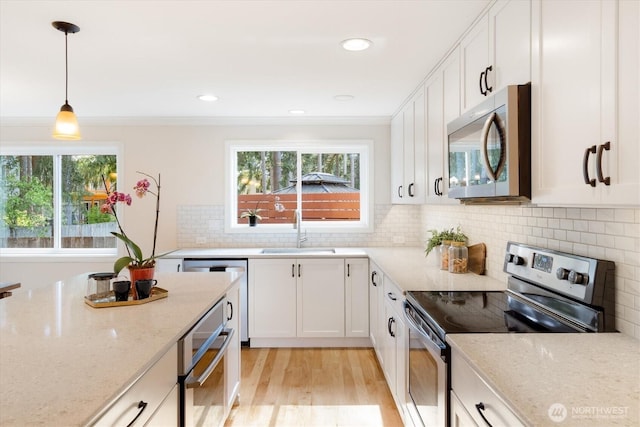 kitchen featuring appliances with stainless steel finishes, a sink, white cabinetry, light stone countertops, and recessed lighting