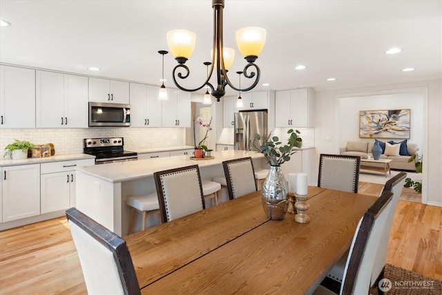 dining space featuring light wood-style flooring, a chandelier, recessed lighting, and crown molding